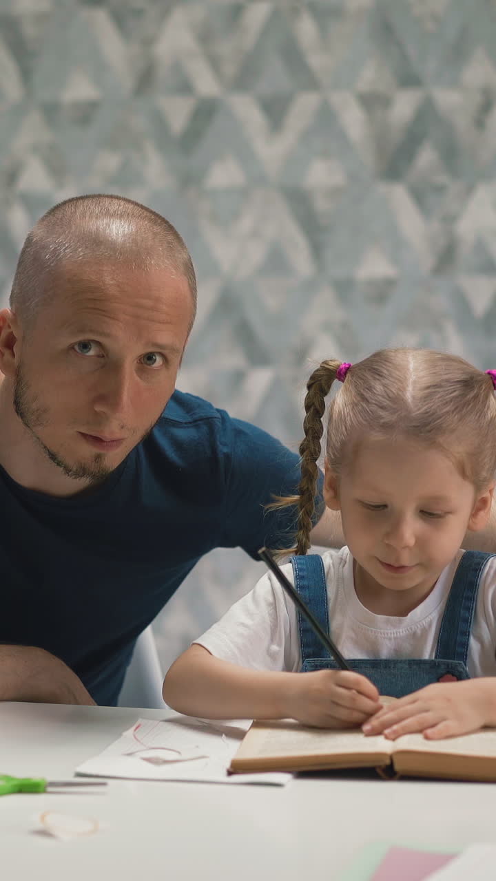 young unshaven dad look little blond daughter student doing homework remotely at home, puts his index finger to lips, looks at camera, gestures quietly, silence, not distracting