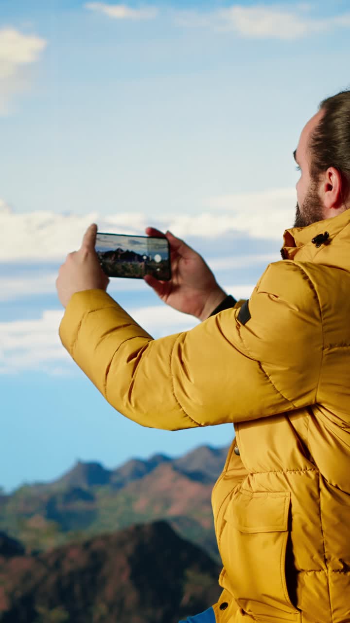 Senderista fotografiando vista panorámica de montaña con teléfono móvil