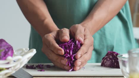 hombre haciendo ensalada, cortando repollo púrpura en rebanadas para ensalada mixta en la cocina