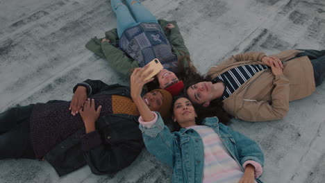 happy friends hanging out lying on rooftop taking selfie photo using smartphone camera enjoying sharing weekend together