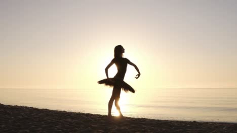 Gorgeous-view-of-a-young-woman-in-dark-tutu-right-in-front-of-the-sea-ocean.-Posing-and-making-ballet-moves.-Sunrise.-Slow-motion