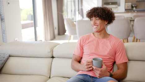 a young biracial man with curly hair relaxes on sofa with copy space