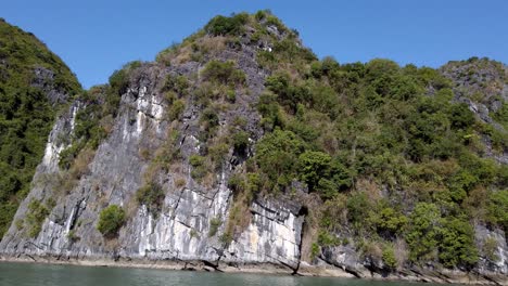 islas montañosas de la bahía de ha long en vietnam hechas de formaciones kársticas de piedra caliza con cielos despejados y sol fuerte, pan izquierda revelan tiro
