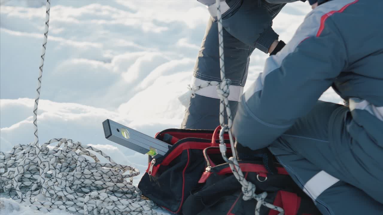 눈이 내리는 상태에서 레벨과 도구를 사용하는 작업자