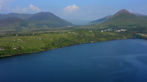 Barnaderg Bay, Letterfrack, Connemara, County Galway, Ireland, July 2021. Drone ascends, revealing view east towards Lough Bunnaboghee and Kylemore in the distance
