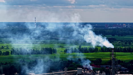 smoke billows from a factory chimney set against a natural landscape backdrop at dusk