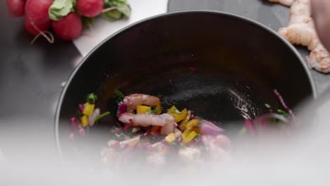 chef prepares cebiche by spooning ingredients into bowl