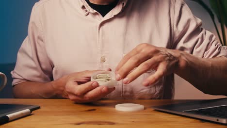 man holding a container of pills at his desk