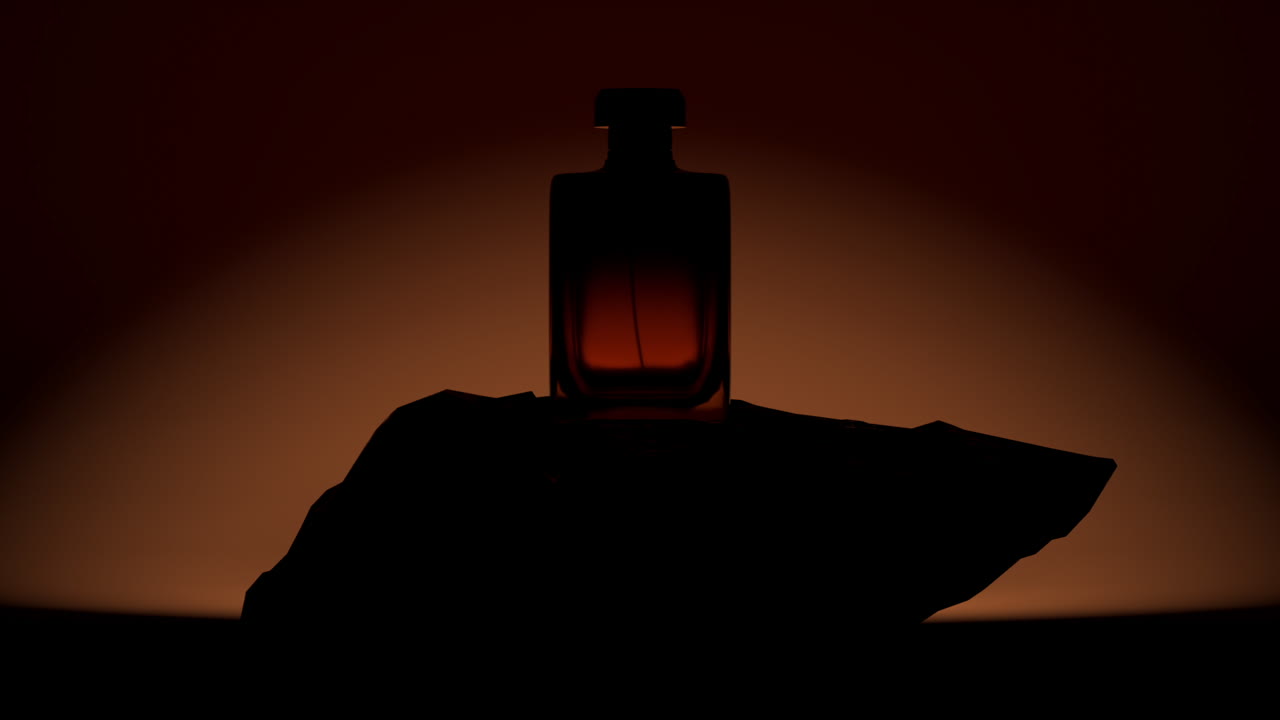 Silhouette di un flacone di profumo luminoso su una roccia con sfondo scuro