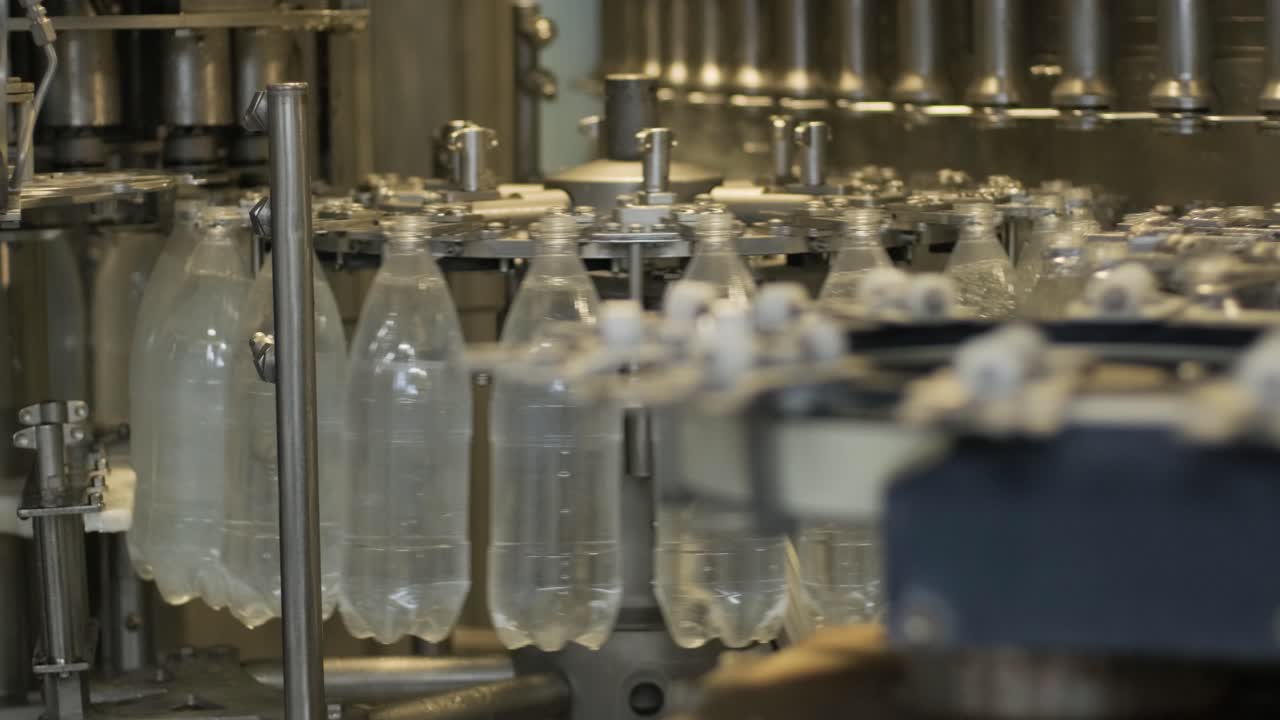 Automatic filling machine pours water into plastic PET bottles at modern beverage plant