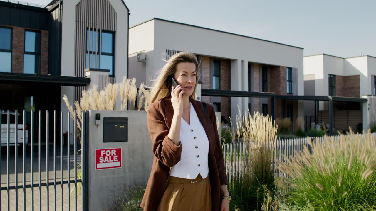 Woman Talking on Phone near Houses for Sale