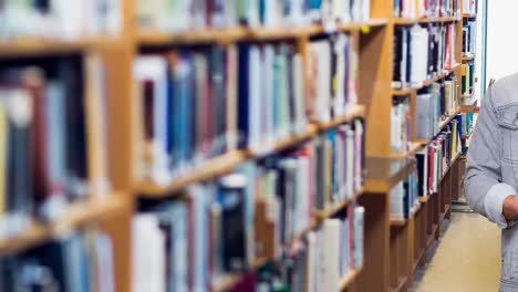 retrato de un estudiante universitario caucásico que sostiene una pila de libros en la biblioteca de la universidad