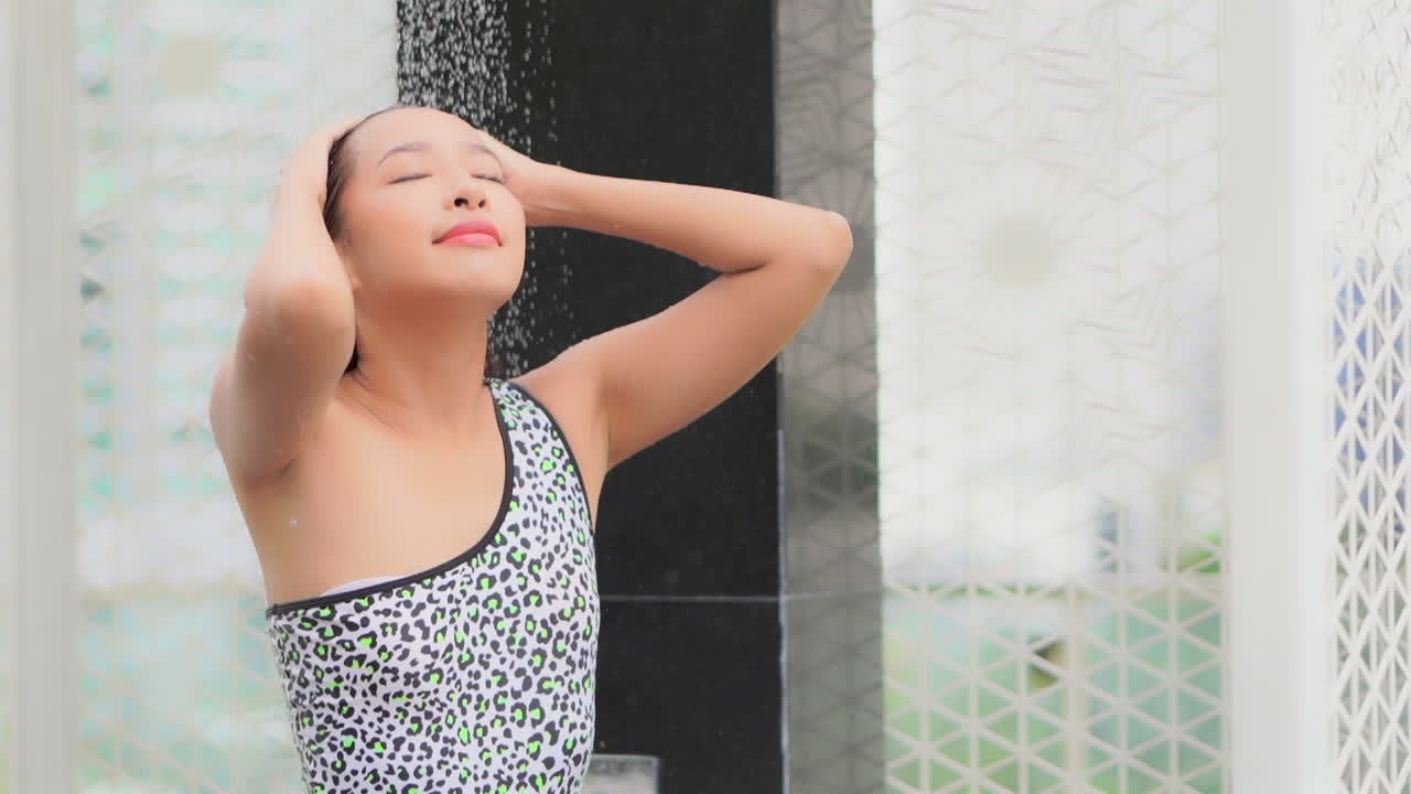 수영복에 매력적인 긴 머리 아시아 소녀는 샤워 슬로우 모션을 엔더 스탠드