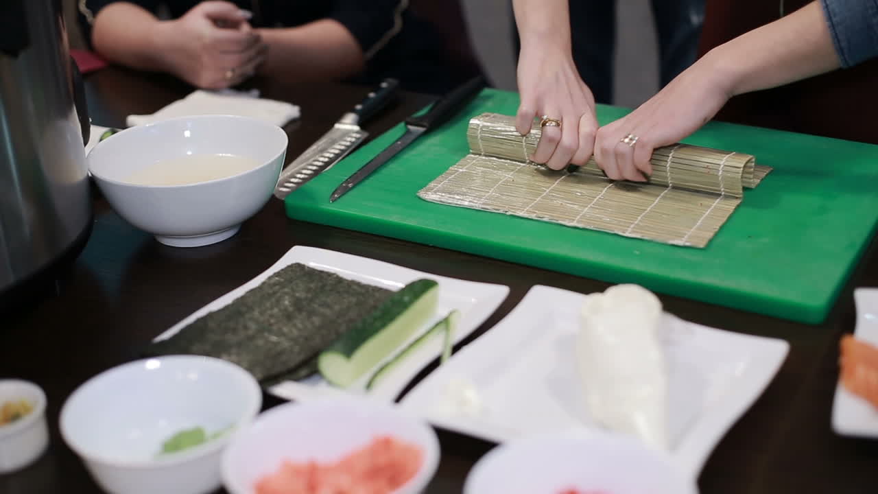 Closeup Of Chef Hands Rolling Up Sushi. Woman chef rolling up a japanese sushi with rice