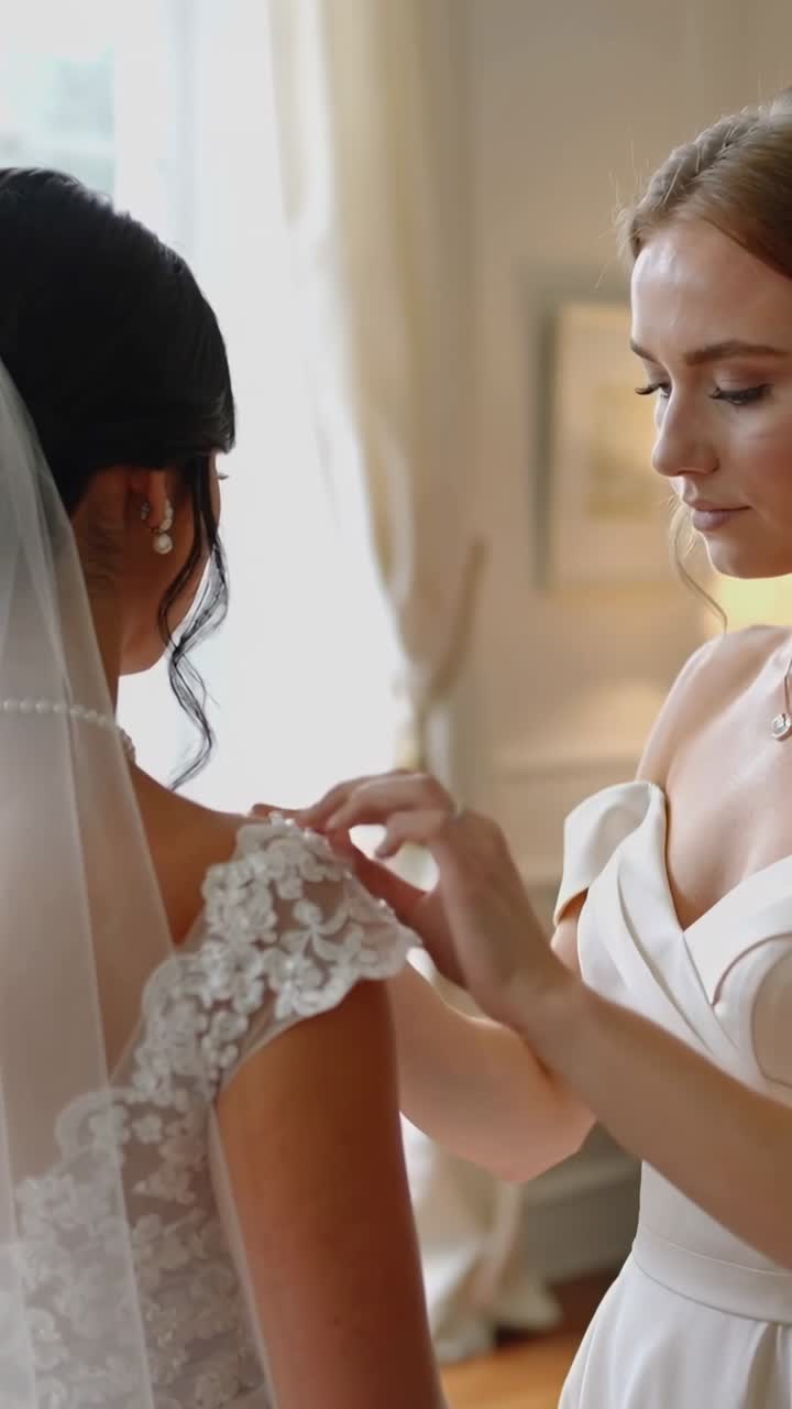 Bridesmaid Helping Bride Adjust Wedding Dress Details