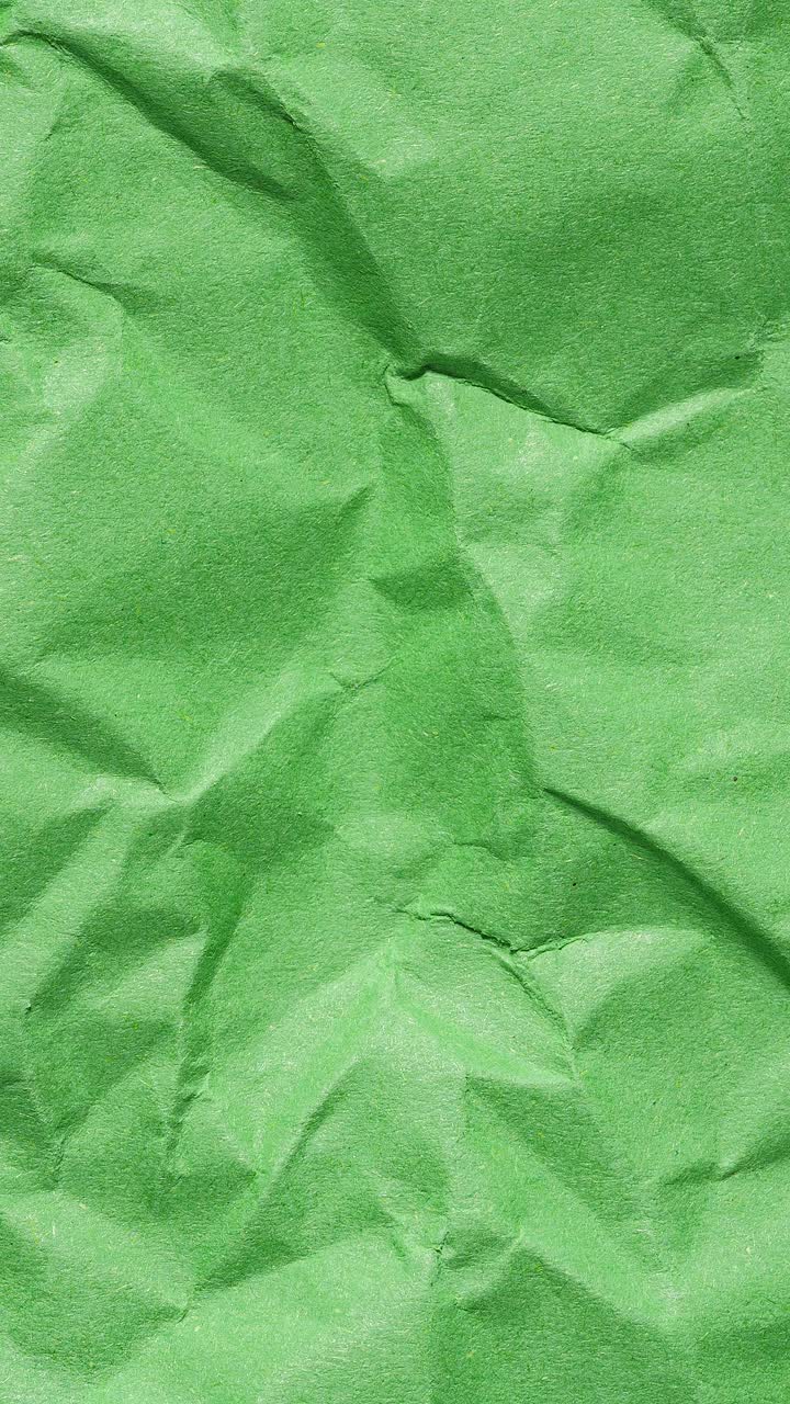 Stop motion animation showcasing a textured green wrinkled paper surface in portrait orientation