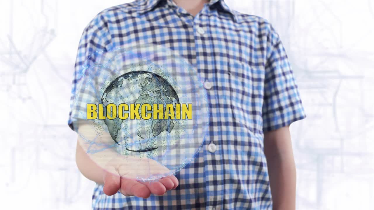 Young man shows a hologram of the planet Earth and text Blockchain