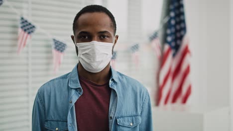 video de un hombre negro con máscara facial en el lugar de votación