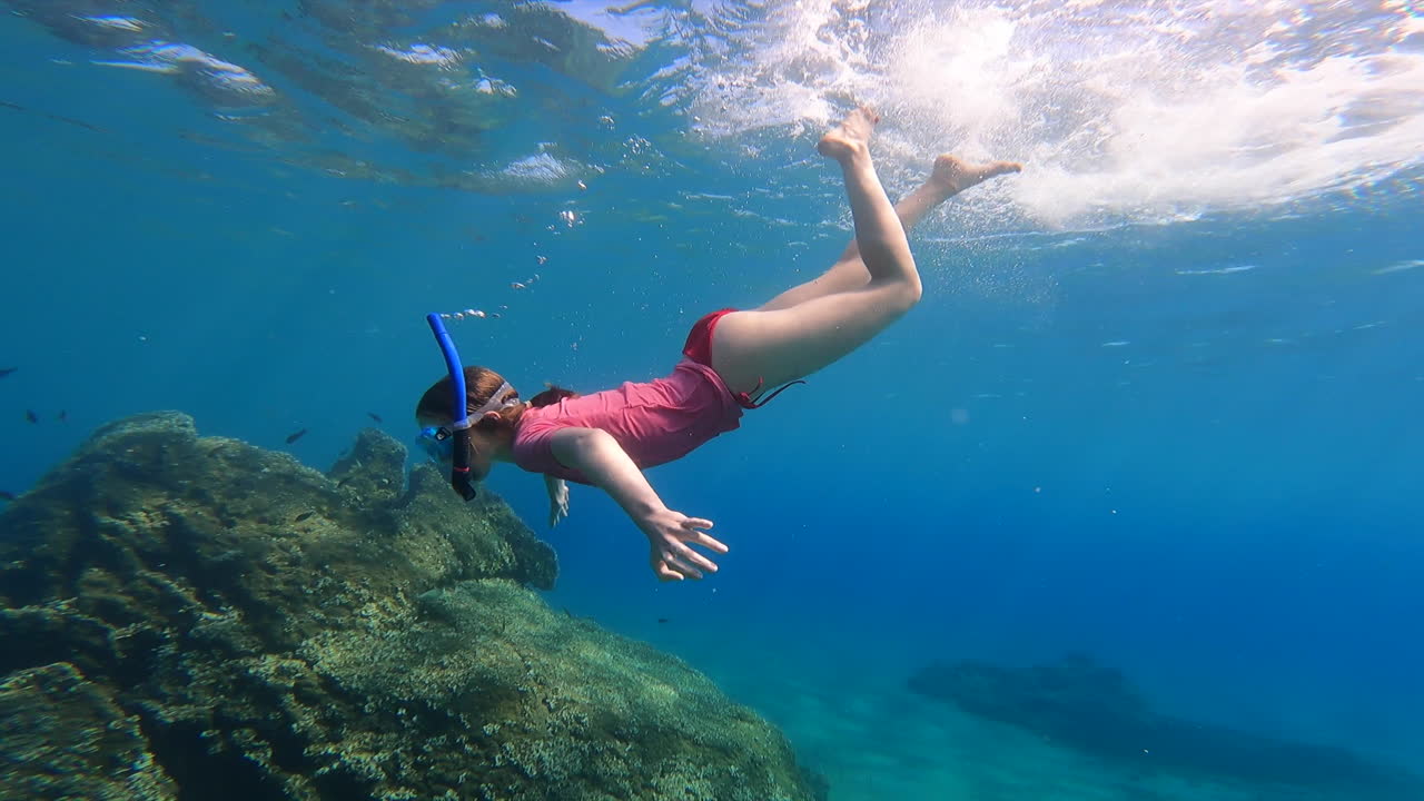 una niña haciendo inmersiones de buceo bajo el agua