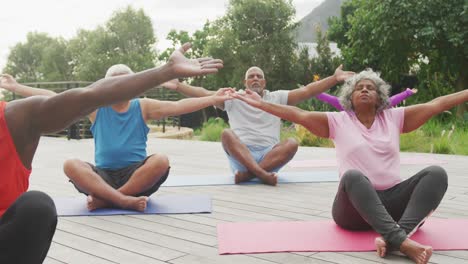 happy senior diverse people practicing yoga in garden at retirement home