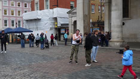 street artist performing in london interacts with a tourist in front of a small crowd