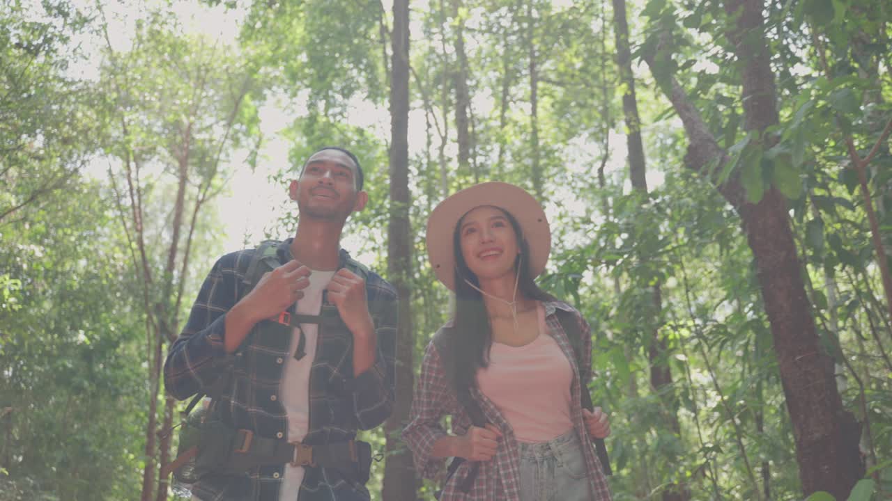 hombre y mujer asiáticos mochilero amigo viajan en el bosque salvaje juntos. atractiva pareja joven viajero caminando y explorando la naturaleza madera con felicidad y diversión durante el viaje de vacaciones de vacaciones en verano.