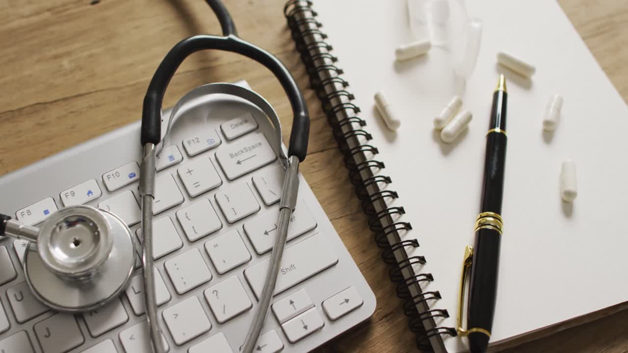 Video of close up of stethoscope with notebook and pills on wooden table