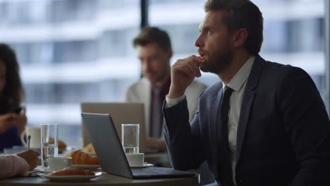 Thoughtful-entrepreneur-working-online-with-coworker-colleague-in-cafe-office.