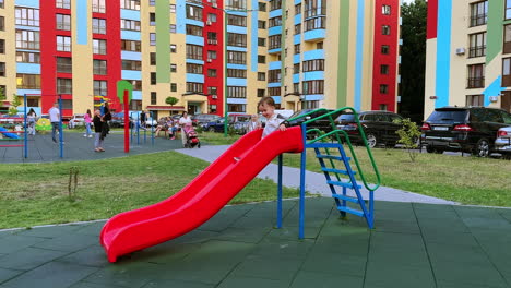 smiling child climbs the slide ladder. happy baby boy slides down and runs to the playground.
