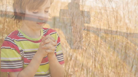 animation of caucasian boy praying and crucifix at sunset