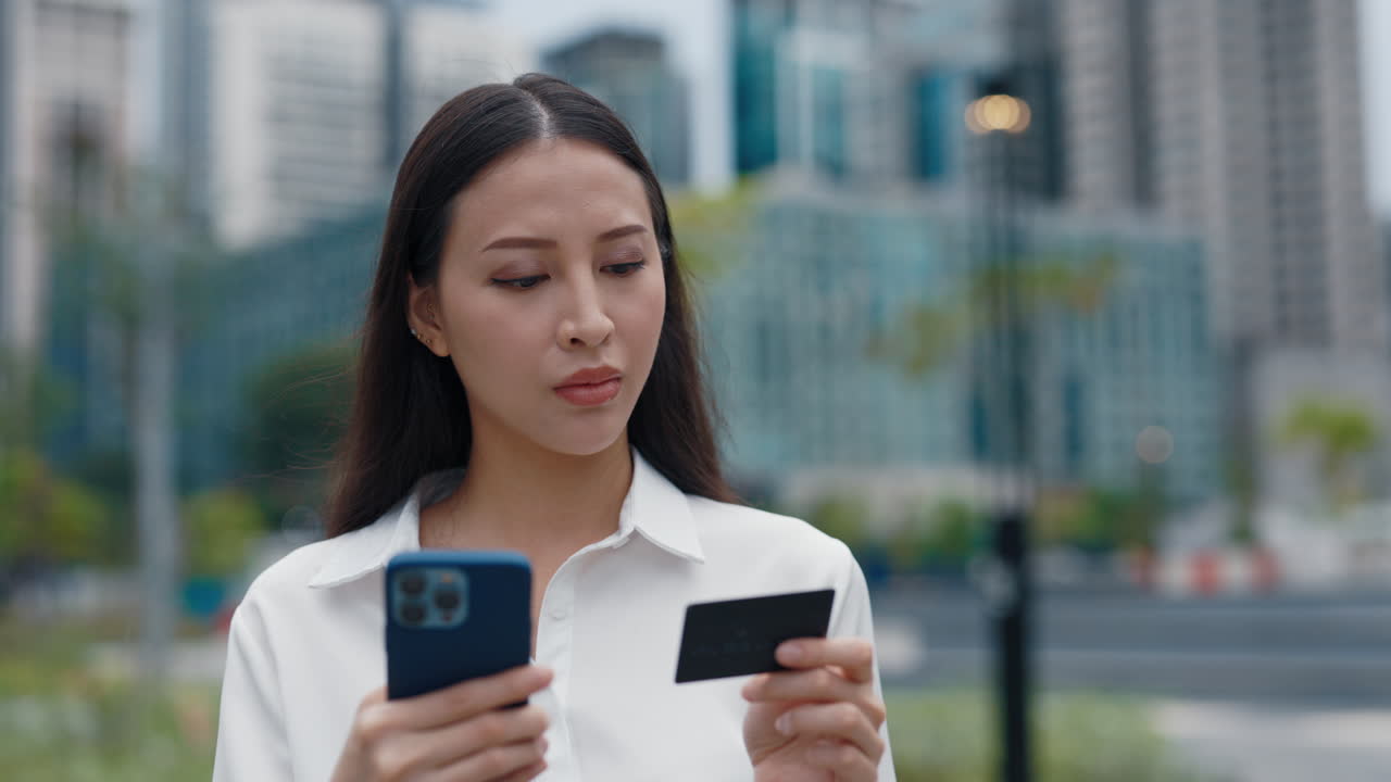 Woman using smartphone and credit card for online shopping in the city