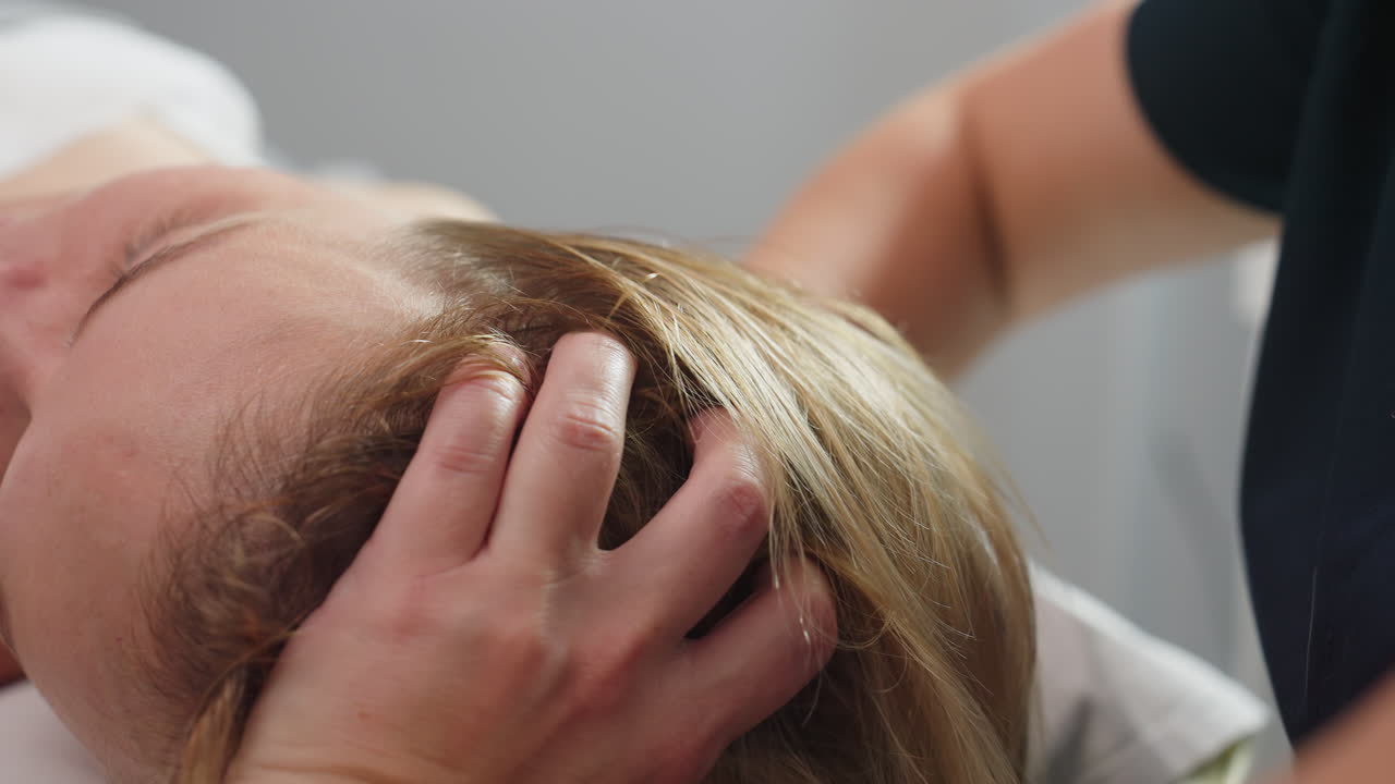 Beauty technician fingers glide from neck to ear as client closes eyes and sighs with relief in serene spa atmosphere, gentle head and ear massage releasing tension and inducing deep relaxation