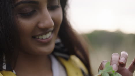 Cerca-De-Un-Insecto-Mariquita-Arrastrándose-Sobre-Una-Hoja-Verde-Una-Joven-India-Sosteniendo-Una-Planta-Sonriendo-Disfrutando-Mirando-A-La-Pequeña-Mariquita