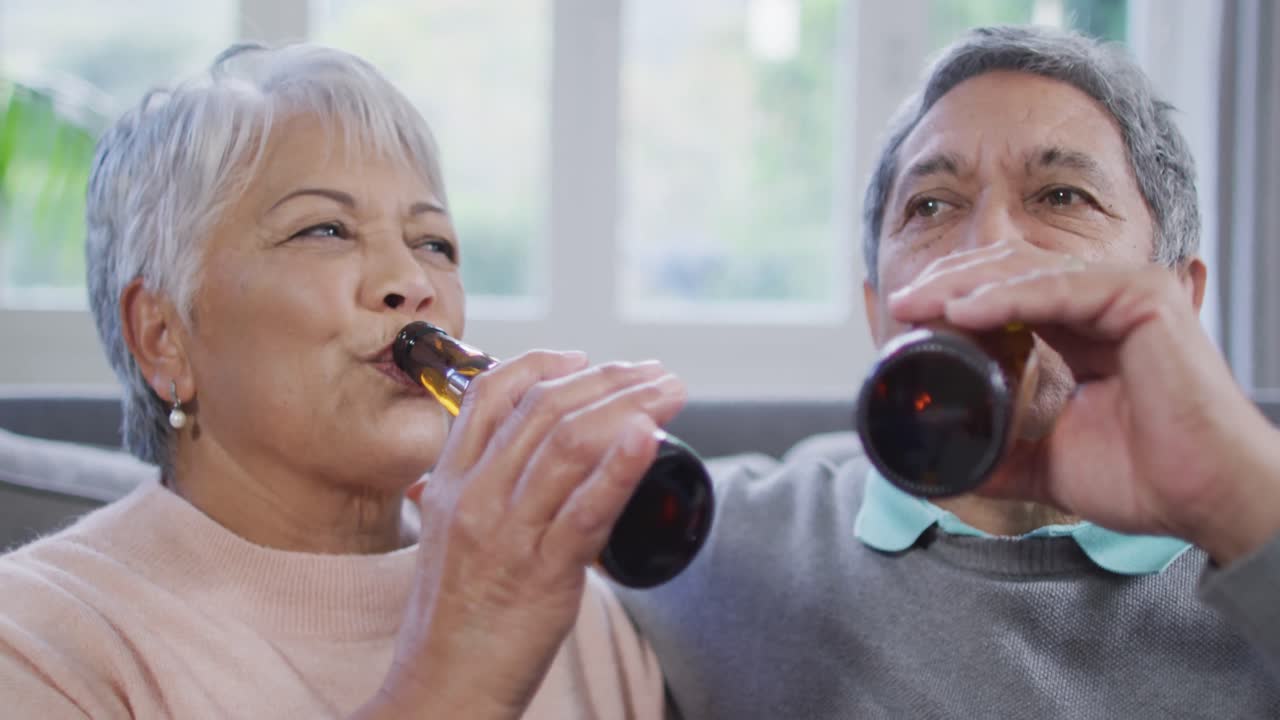행복한 혼성 인종의 노인 커플이 맥주를 마시고 재미를 느끼고 있습니다.