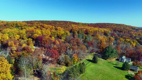 a high angle aerial view over the quiet countryside of new jersey with colorful trees all around on a sunny day in autumn