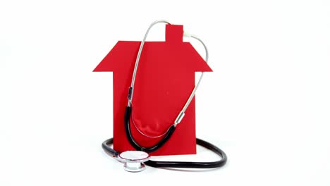 Close-up-of-house-model-and-stethoscope-against-white-background