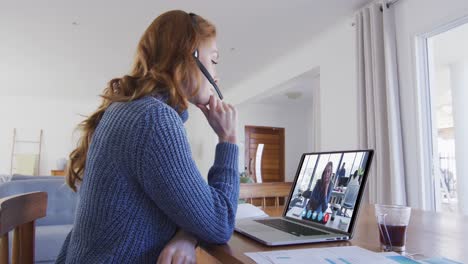 mujer caucásica usando portátil y auriculares de teléfono en videollamada con una colega