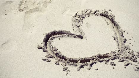 girl draws a heart on the sea sand. the waves wash away the heart drawn on the sand.