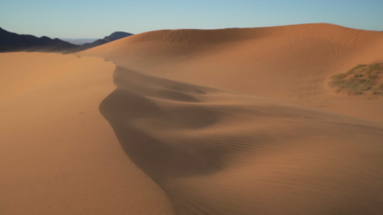 viento fuerte en cámara lenta que sopla arena y polvo sobre grandes dunas de arena en el calor del verano aislado