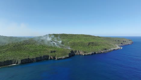 fotografía aérea de un incendio forestal en una isla tropical con agua de mar azul