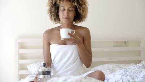 Attraktive-Frau-Mit-Einer-Tasse-Kaffee-Auf-Dem-Bett