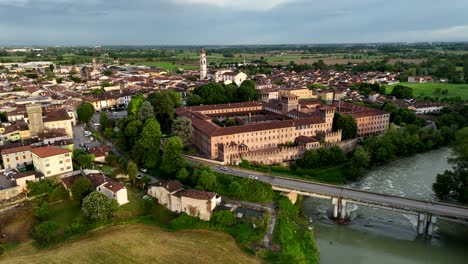 panoramic aerial drone view of the historic town center of pontevico italy featuring the medieval castle over the oglio, prominent church tower and under a partly cloudy sky at sunset