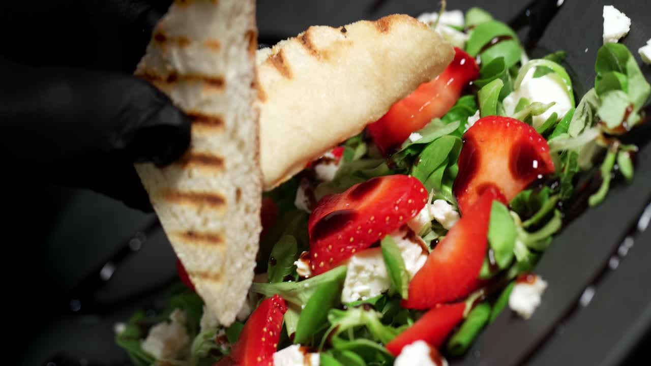 A salad with lamb&acute;s lettuce, strawberries, feta and balsamico is served with bread