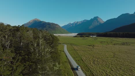 aerial view rising over campervan traveling though rugged mountainous landscape in dart valley, glenorchy, south island of new zealand aotearoa