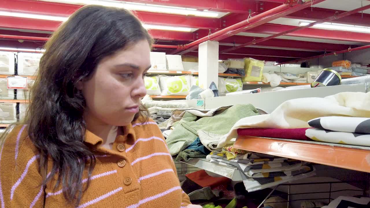 Young adult woman shopping for home goods, examining towels and bed linen