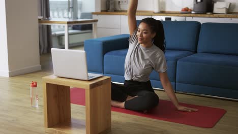 Young-African-woman-doing-stretching,-warming-up-her-joints-in-front-laptop,-slow-motion