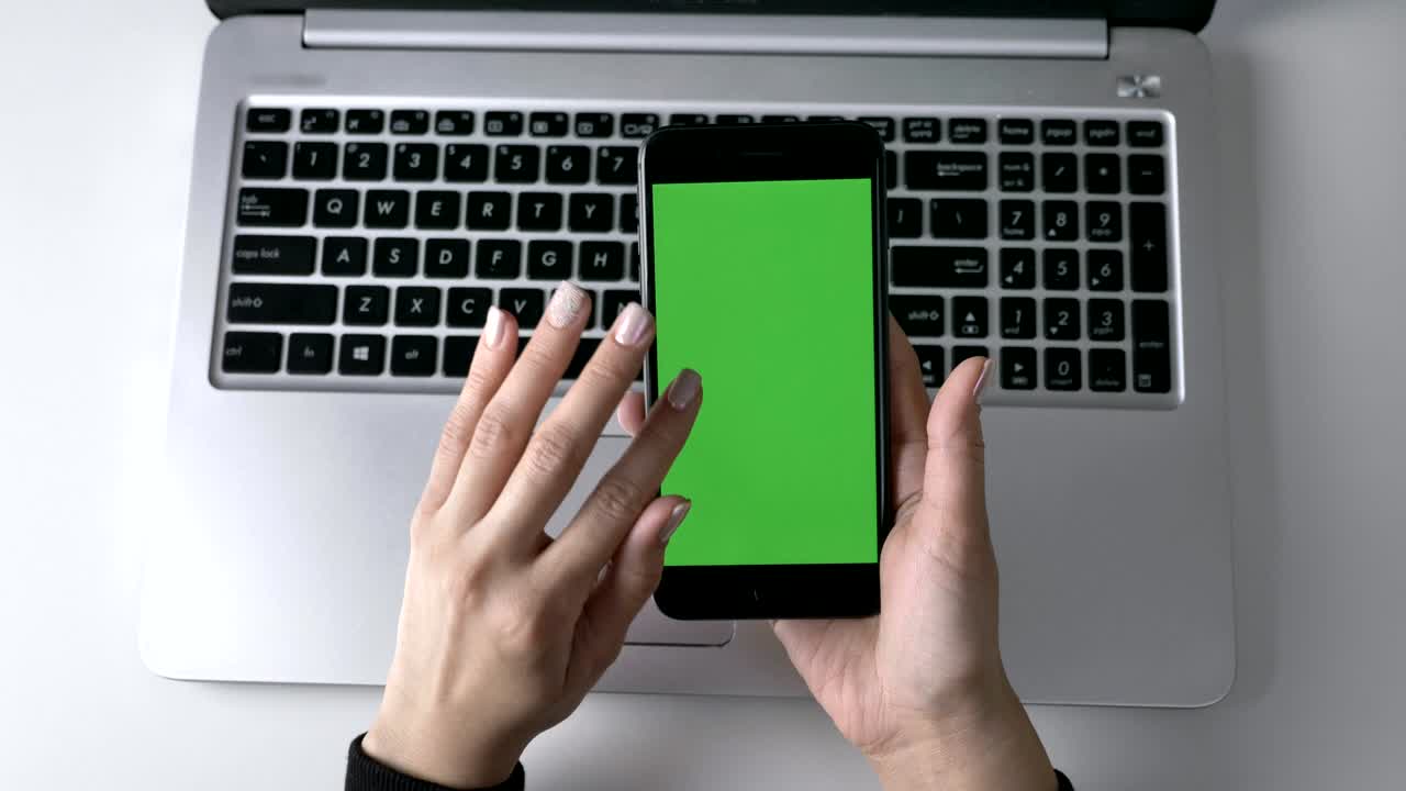 manos femeninas desplazándose en la pantalla táctil del teléfono inteligente. pantalla verde, concepto chromakey, portátil en el fondo. top shot 60 fps