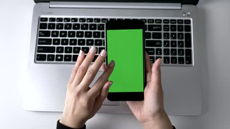 manos femeninas desplazándose en la pantalla táctil del teléfono inteligente. pantalla verde, concepto chromakey, portátil en el fondo. top shot 60 fps