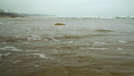 A-low-shot-of-the-damp-sand-as-white-wash-from-the-waves-slowly-creep-into-shot