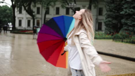 cheerful woman taking off her umbrella to enjoy the rain in the city